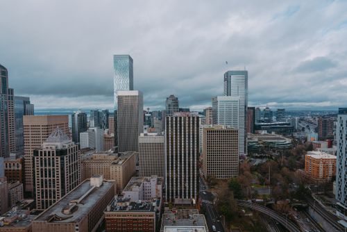 Free Aerial view of a modern city skyline on a cloudy day, showcasing skyscrapers and urban architecture. Stock Photo