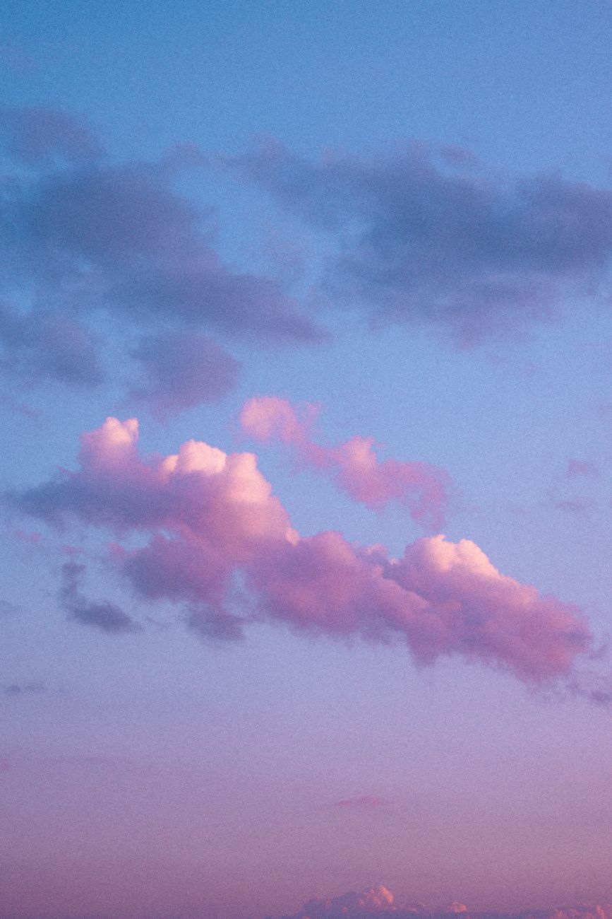 Serene pastel clouds in a vibrant pink and purple sky at sunset, creating a peaceful atmosphere.