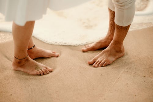 A couple standing on the beach with their feet in the sand