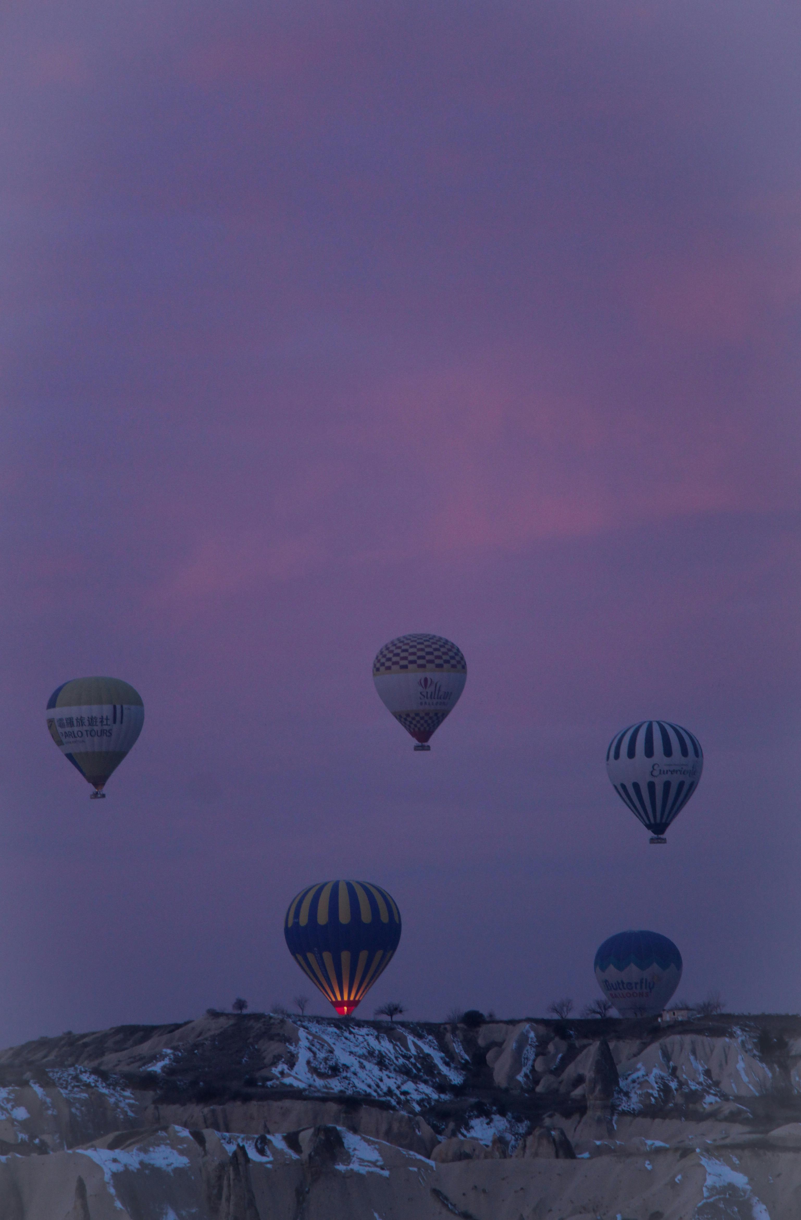 Captivating view of hot air balloons floating over Göreme, Türkiye during sunset.