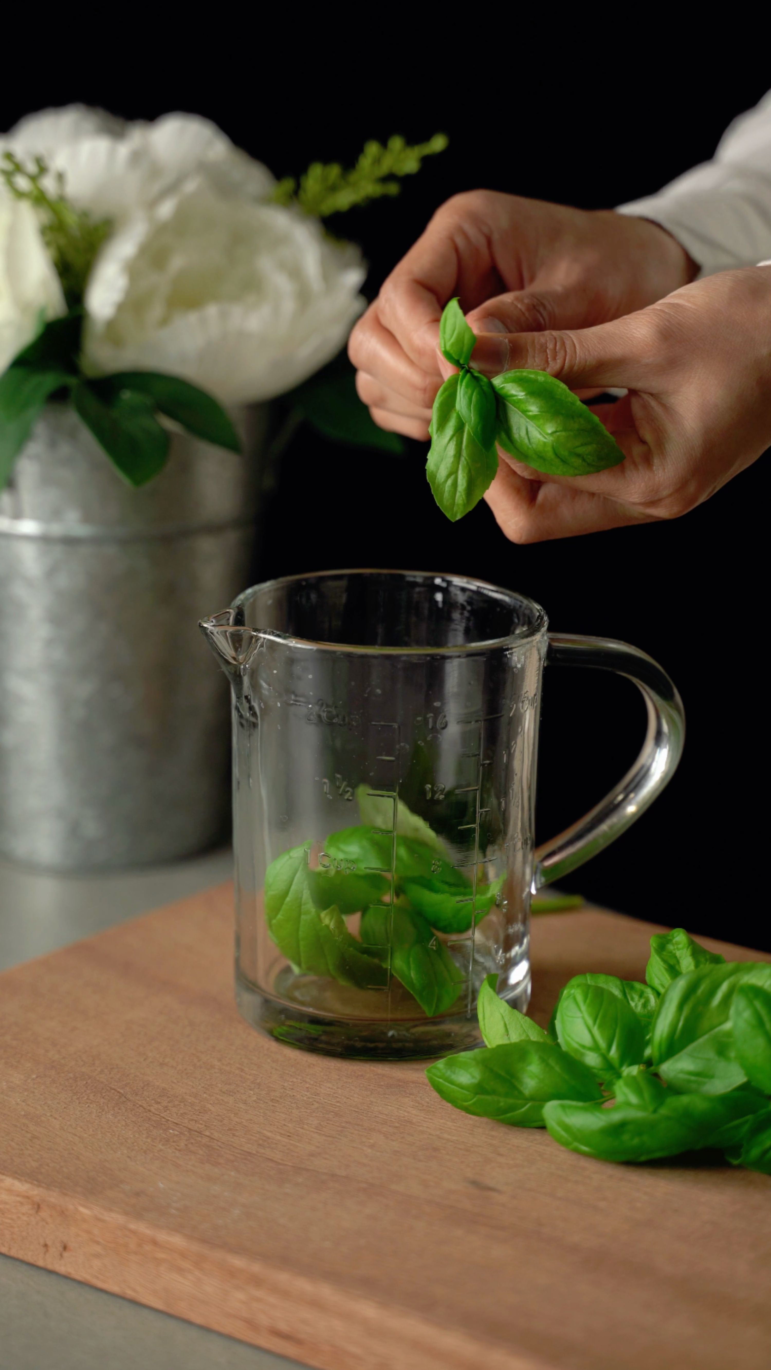 Fotomural Manos preparando albahaca fresca en el medidor para cocinar.