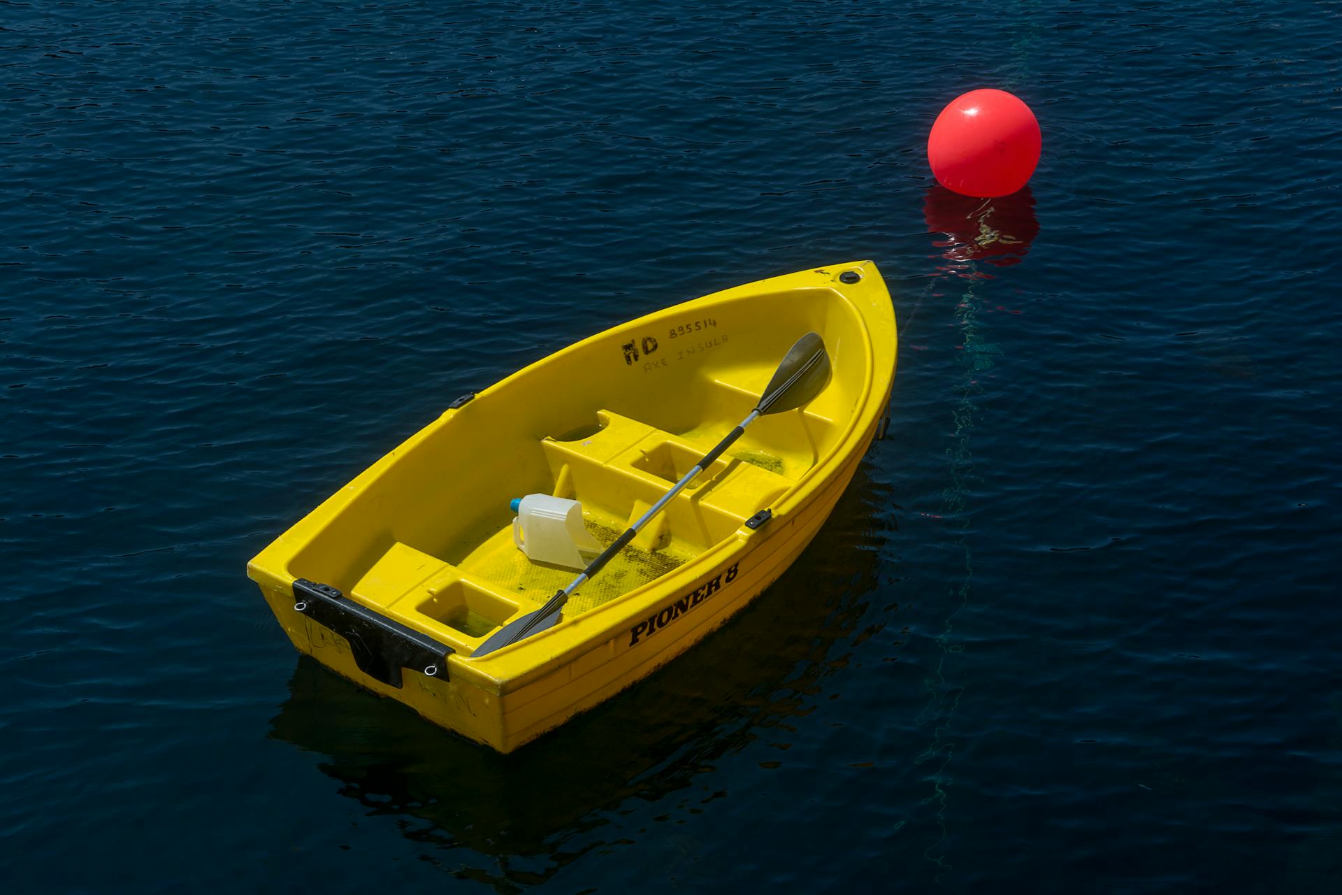 Yellow Boat and a Red Buoy on Blue Lake Water