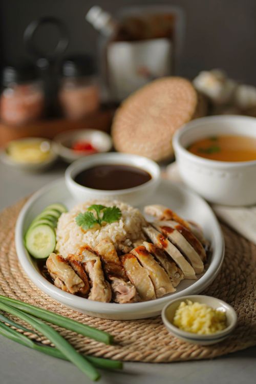 Free Close-up shot of a delicious Hainanese chicken rice meal served with soup and sauces. Stock Photo