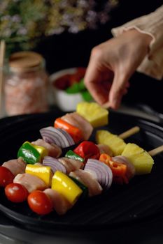 A person arranging colorful vegetable and chicken skewers in a close-up shot.