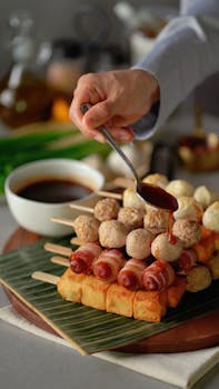 Delicious skewered meatballs being drizzled with sauce in a close-up food shot, perfect for gourmet food photography.