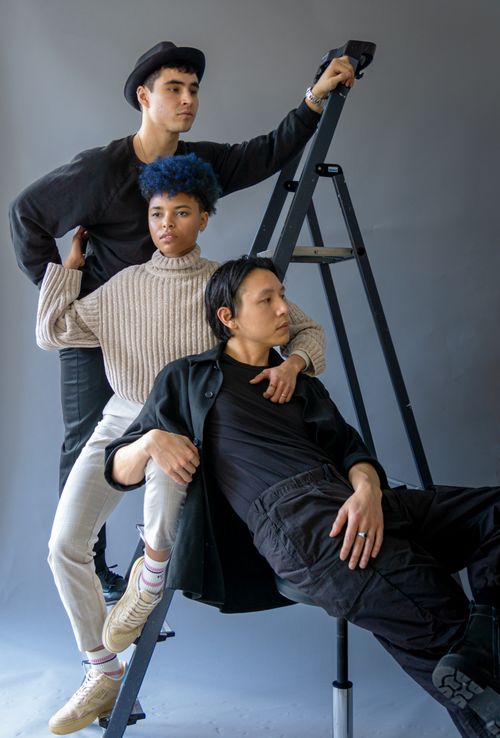 Free A diverse group of young adults posing creatively in a studio setting with a ladder. Stock Photo
