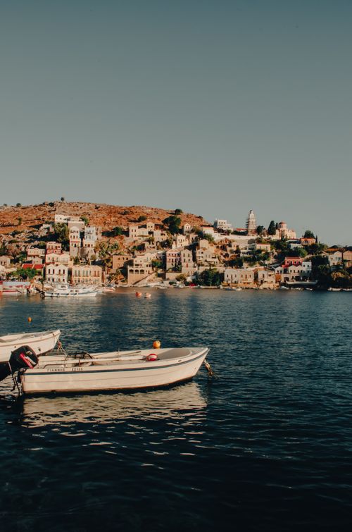 Free Scenic view of a Greek coastal town with boats floating on the calm sea, showcasing traditional architecture. Stock Photo