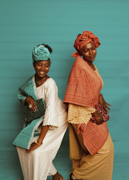 Two Elegant Women in Maxi Dresses and Headscarves Posing in a Studio