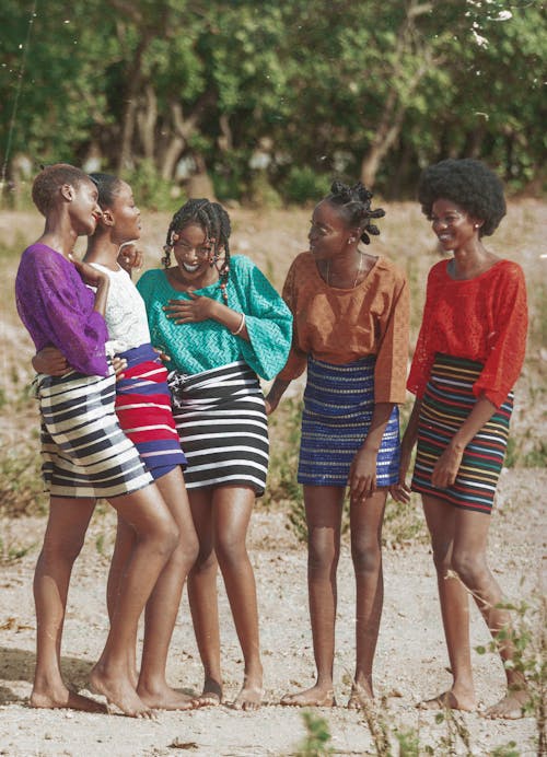Group of Young Women Posing in Striped Skirts and Colorful Blouses