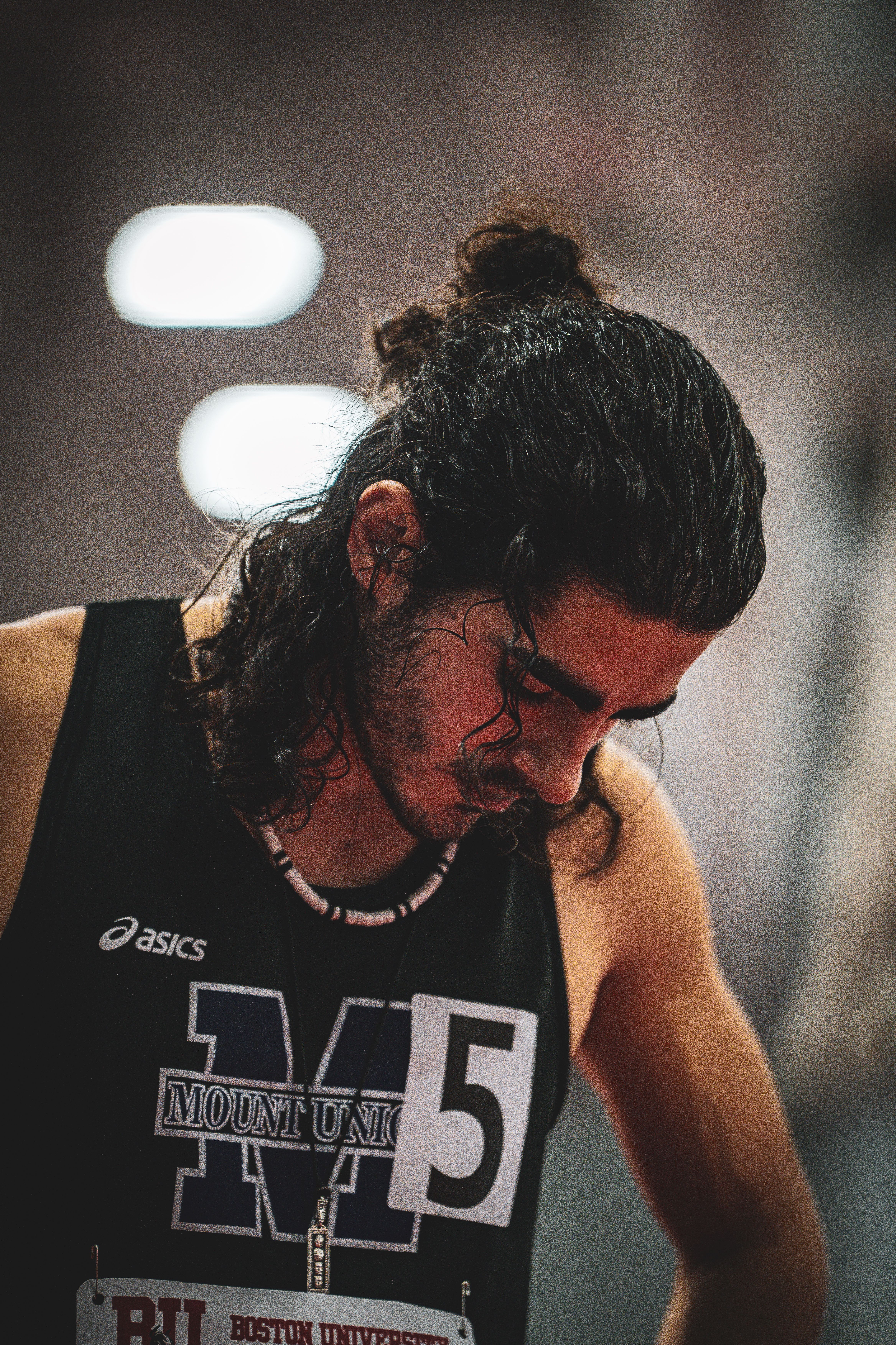 Focused athlete with long hair at Boston University indoor sports event.