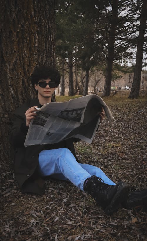 A Woman Reading a Newspaper Under the Tree