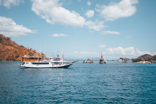 Free Traditional ships sailing in the clear waters of Komodo, Indonesia under a sunny sky. Stock Photo
