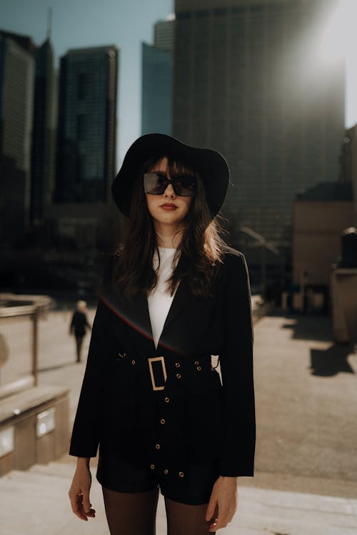A woman in a black hat and jacket standing in front of a city skyline