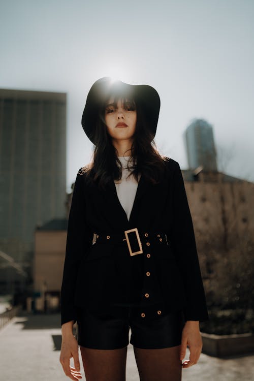 A woman in a black hat and shorts standing in front of a city