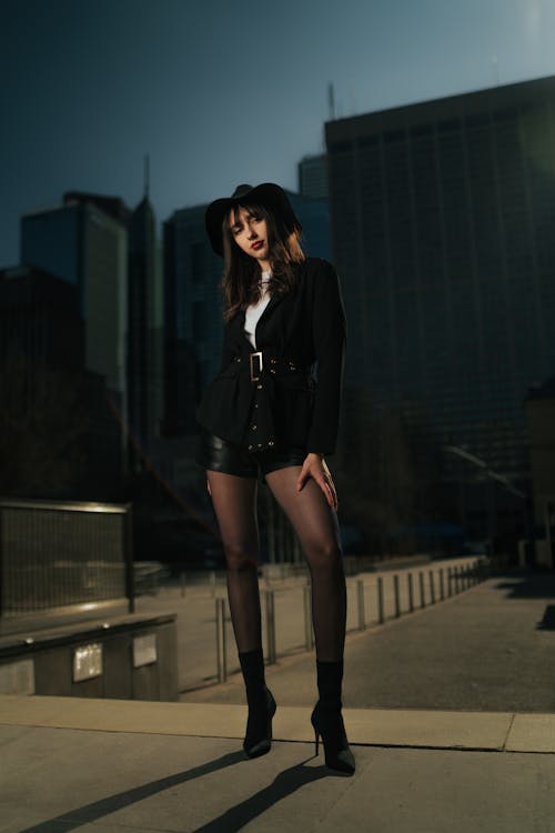 A woman in a hat and black stockings posing in front of a city skyline