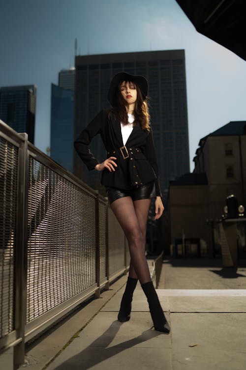 A woman in black shorts and a jacket posing on a bridge