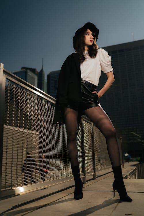 A woman in tight stockings and a hat posing on a bridge
