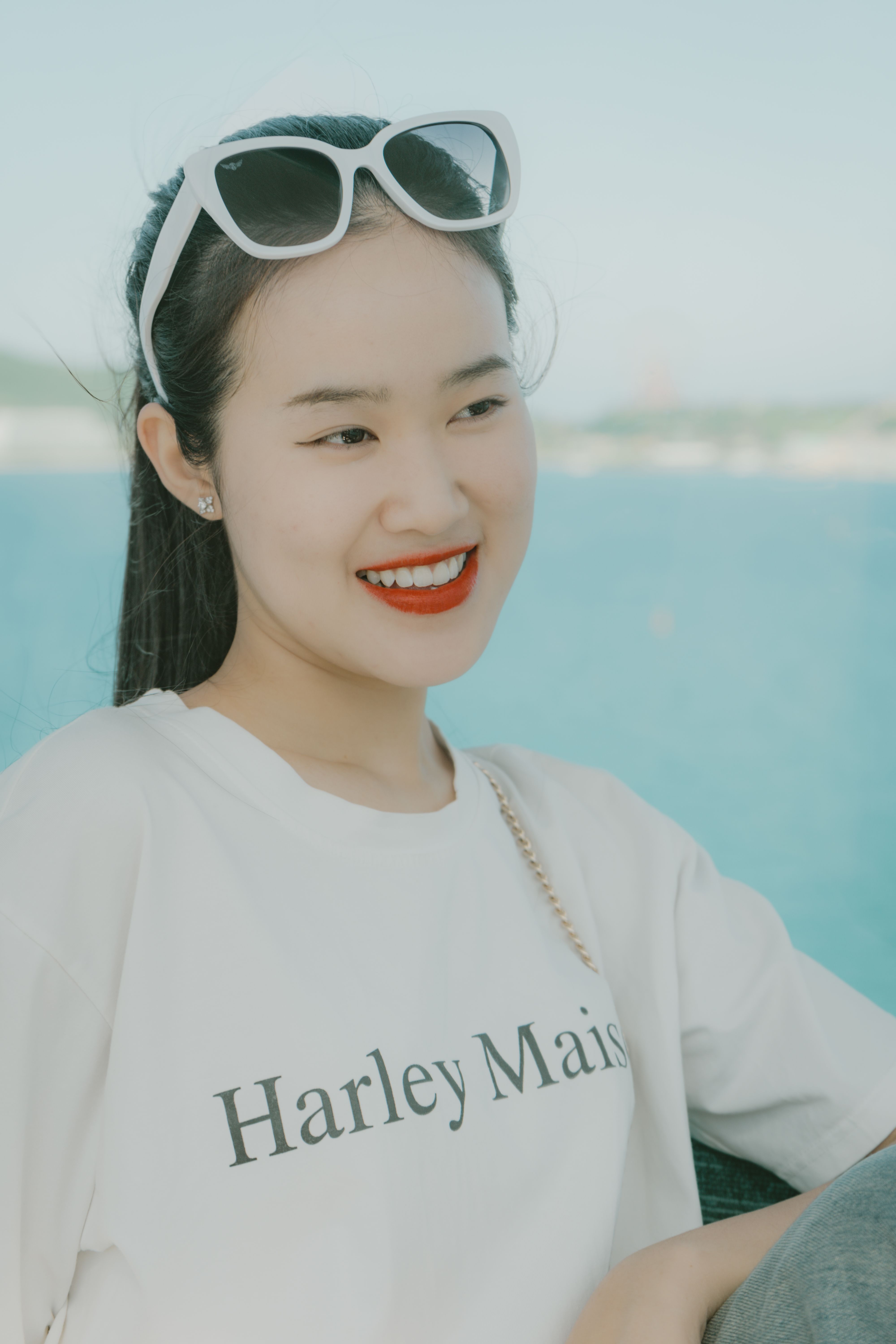 A stylish woman in sunglasses is smiling outdoors, showcasing modern fashion.