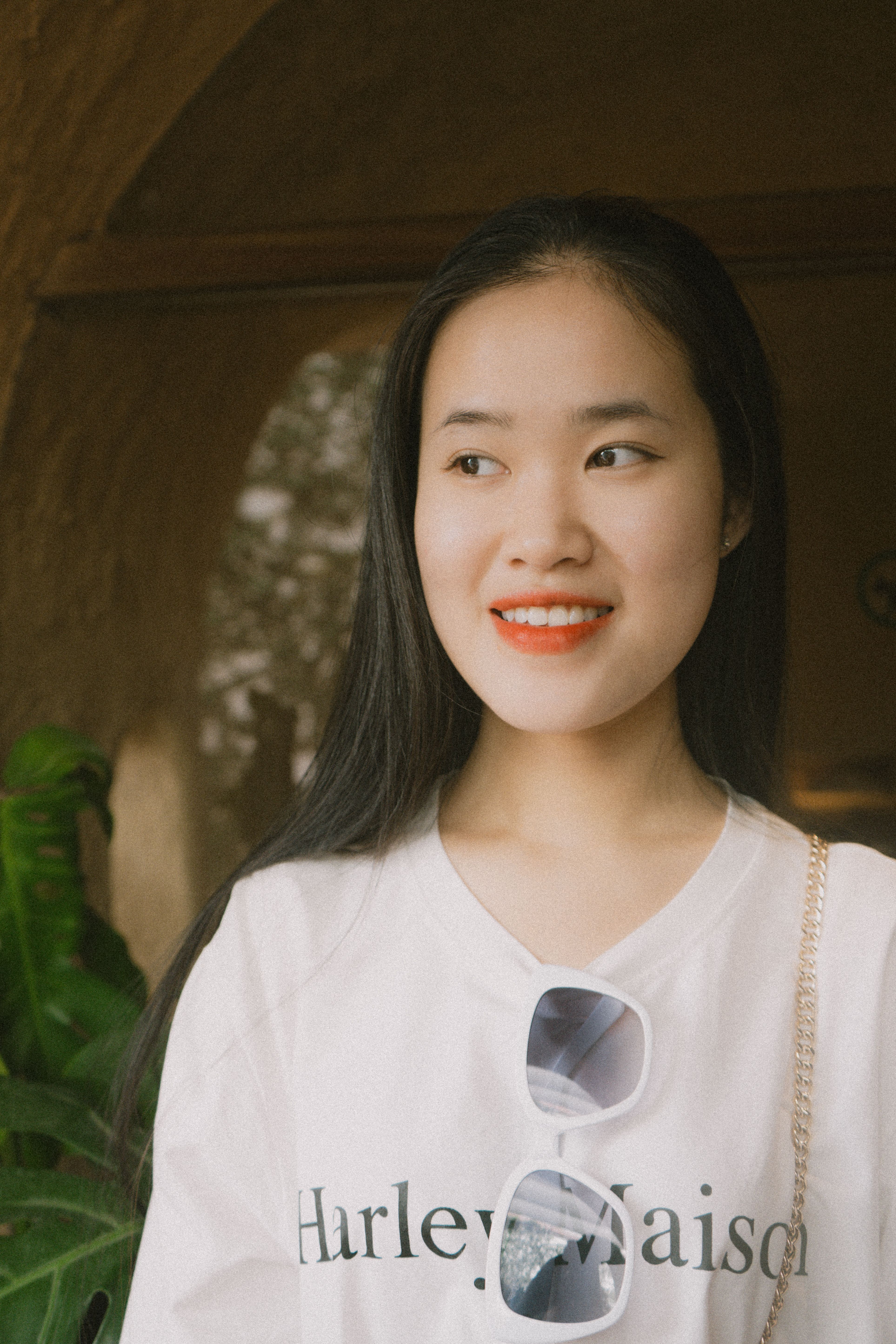 Smiling Asian woman with black hair wearing white shirt and sunglasses
