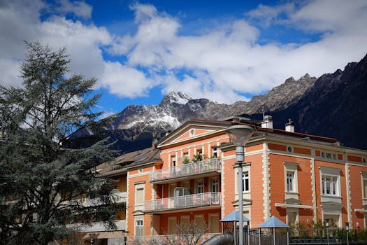 Photograph of a classy architecture building in Meran, Italy, set against a stunning mountain range.
