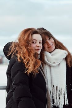 Two women smiling and embracing outdoors in winter, Jönköping, Sweden.