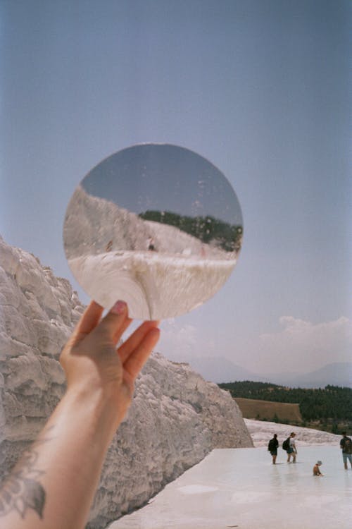 A person holding a mirror in front of a mountain