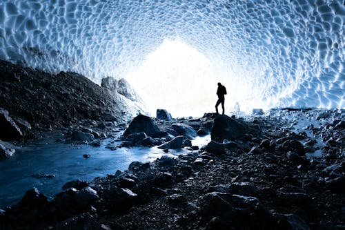 Silhouette of a Person Standing in an Ice Cave
