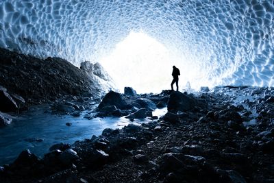 Walker silhouetted inside a blue ice cavern — photo by Julien R on Pexels