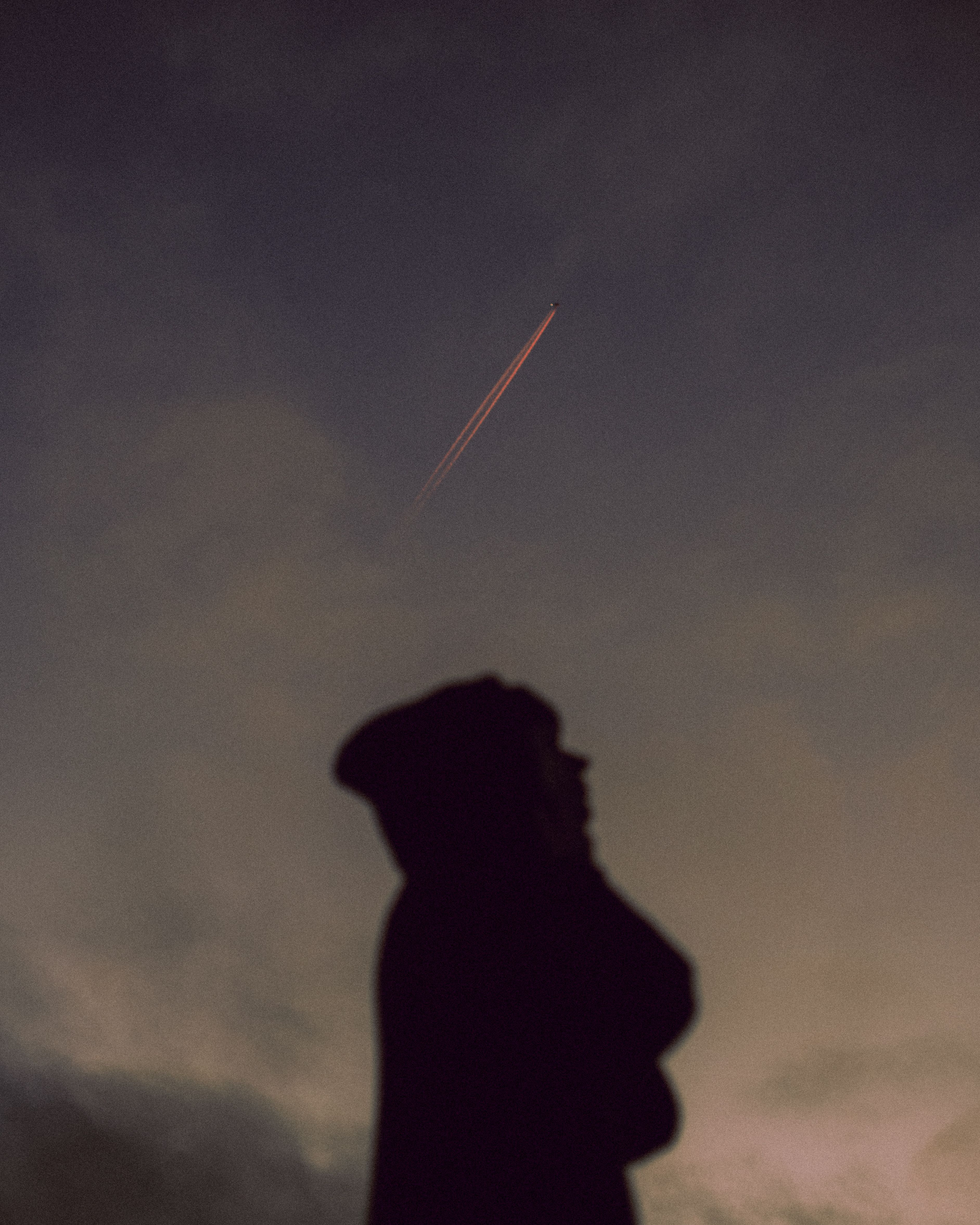 A dramatic silhouette under a night sky with visible airplane contrail, evoking mystery and wonder.. pexels, dramatic, silhou