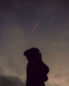 A dramatic silhouette under a night sky with visible airplane contrail, evoking mystery and wonder.. pexels, dramatic, silhou