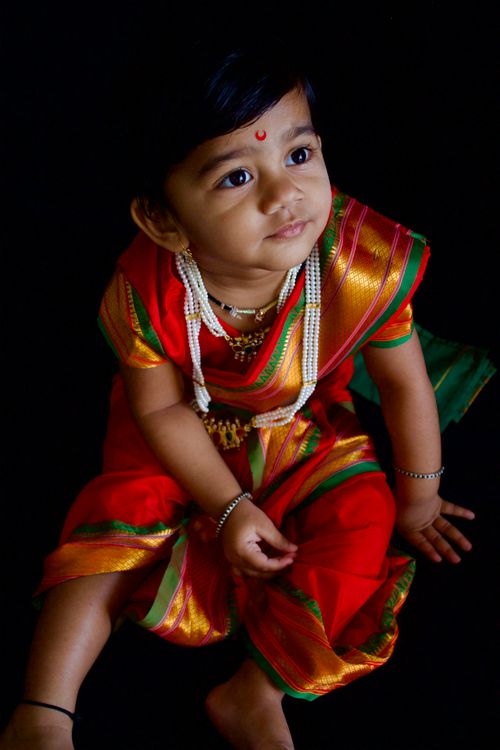 Free A young girl in vibrant traditional Indian attire sits gracefully, capturing cultural essence. Stock Photo