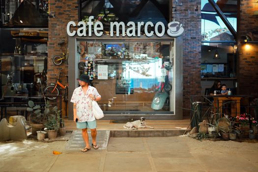 Street view of Café Marco with a pedestrian and dog, capturing urban relaxation and charm.