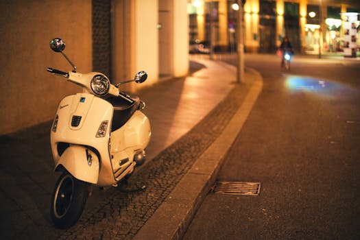 A white scooter parked on a Berlin street, illuminated by warm city lights at night.