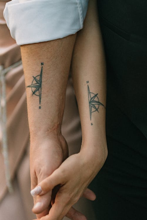 Two people holding hands with tattoos on their arms
