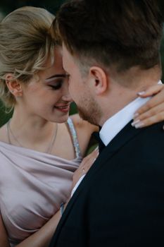 Close-up of a smiling couple in formal attire embracing at an outdoor event.