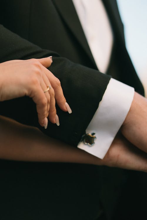 A close up of a man's hand holding a woman's wedding ring