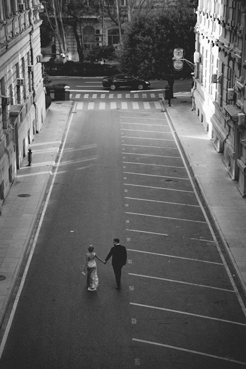 A black and white photo of a couple walking down a street