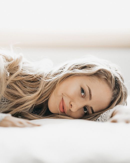 Smiling woman with long blonde hair relaxing indoors, exuding serenity and warmth.