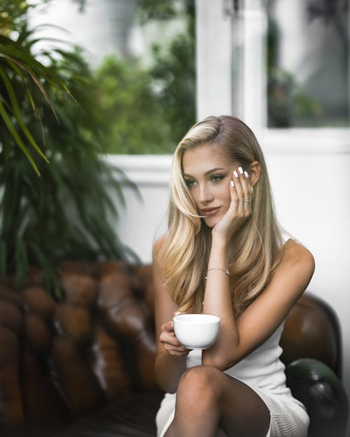 Blonde Woman Sitting with Hand on Cheek