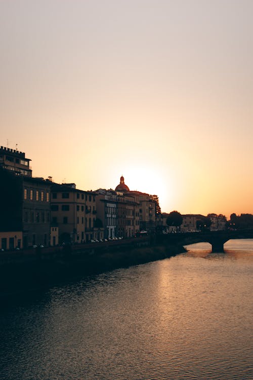 A sunset over a river with buildings in the background