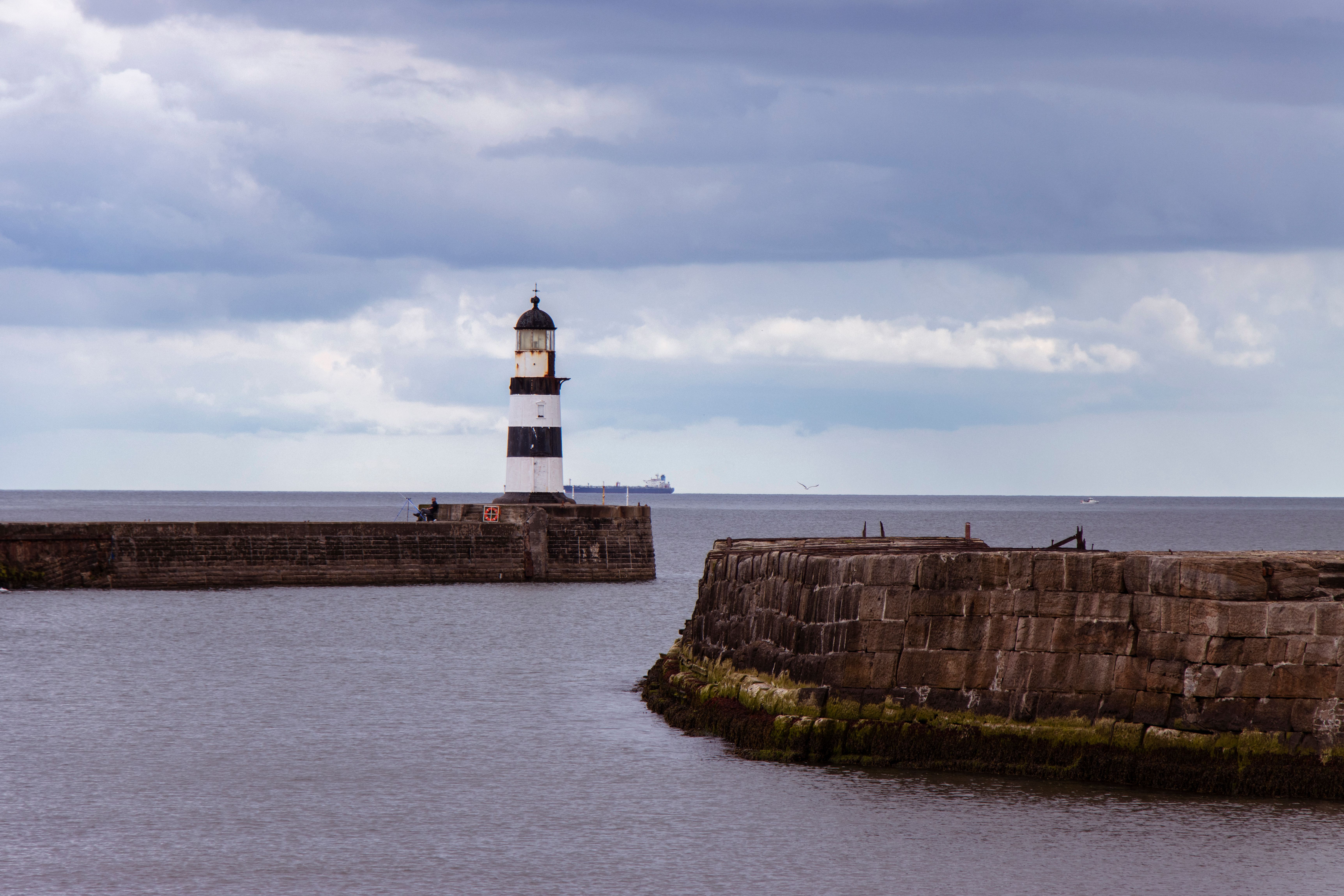 A scenic view of Seaham Lighthouse against a cloudy sky at the waterfront in England.
