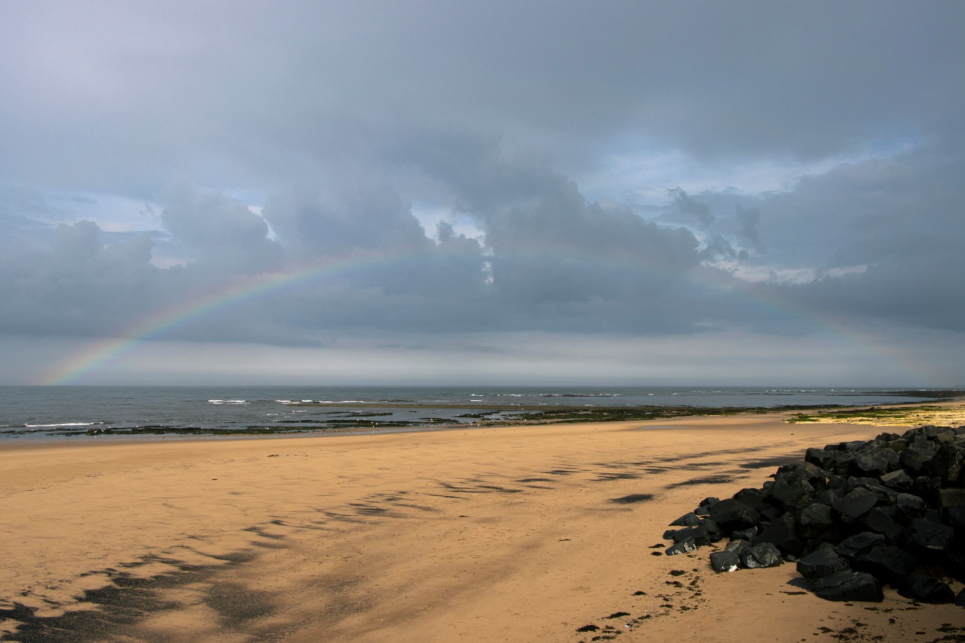 Beautiful beach scene with rainbow and clouds at Seaham, UK. Perfect nature and serenity.