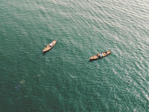 Free A serene aerial image showcasing two wooden boats floating on a turquoise sea, capturing tranquility from above. Stock Photo