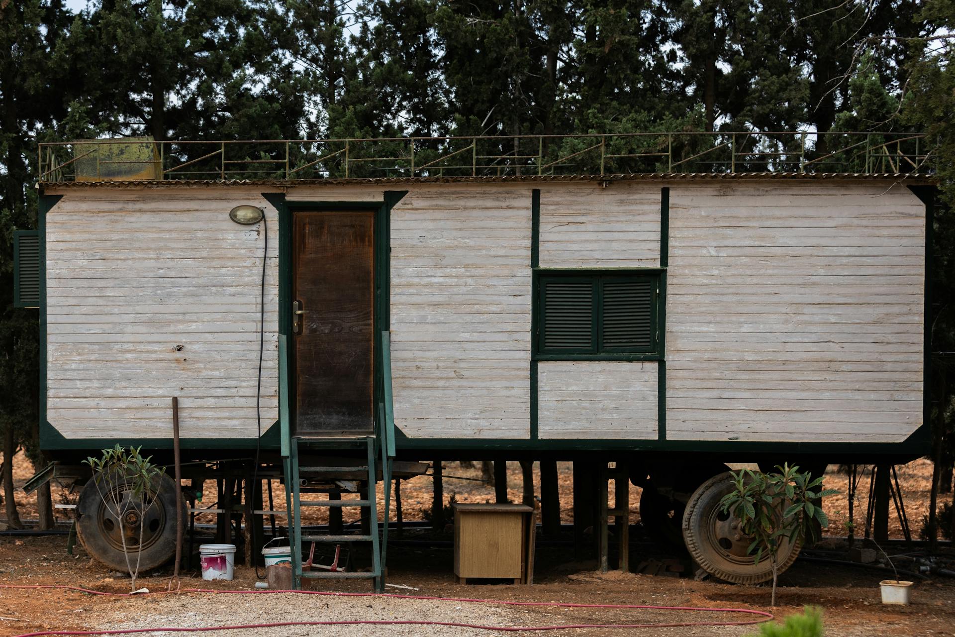 A rustic wooden trailer situated outdoors amongst tall trees. Ideal for rural and nature-themed projects.