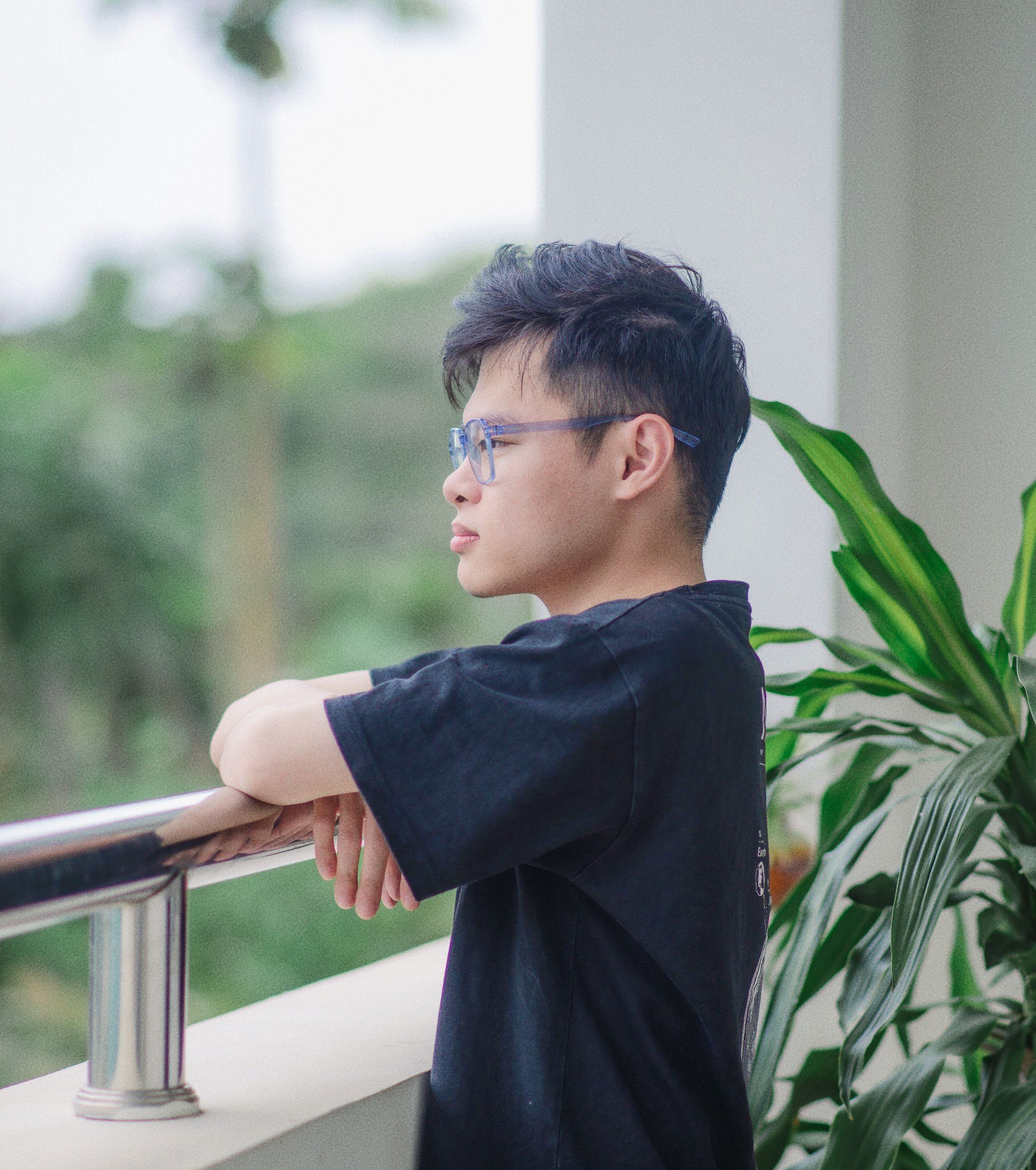 Profile of a man enjoying a peaceful moment on a balcony surrounded by greenery.