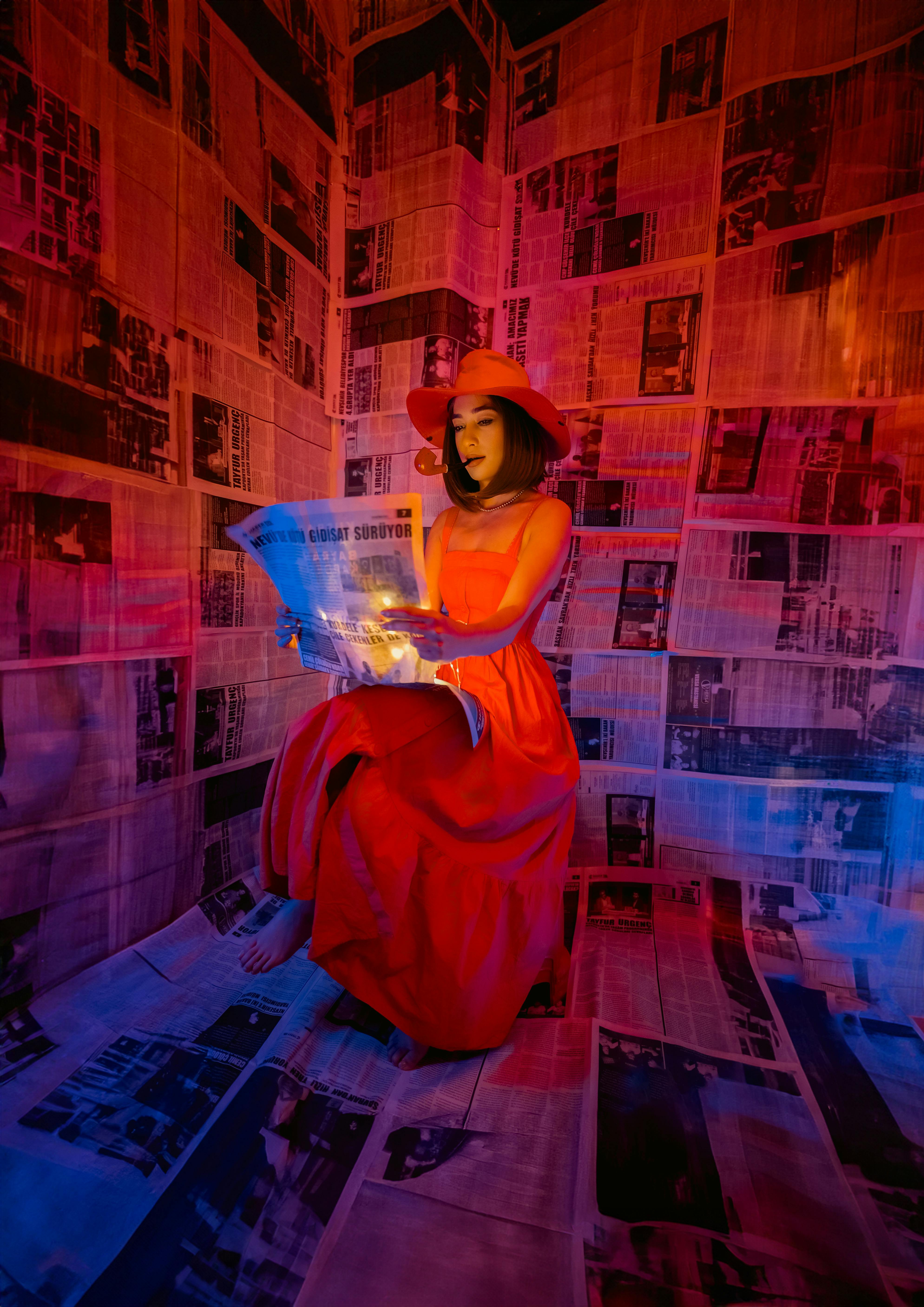 model in elegant dress and hat smoking pipe while reading newspaper