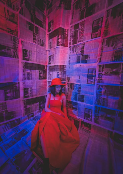 A woman in a red dress sitting in a room with newspaper