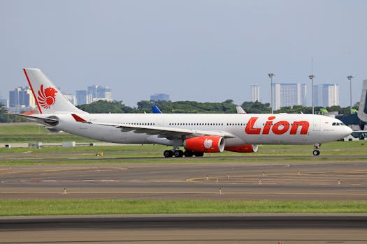 Lion Air passenger aircraft on airport runway with cityscape background.