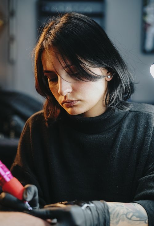 Free A skilled female tattoo artist concentrates on her design work in a studio in İzmir, Türkiye. Stock Photo