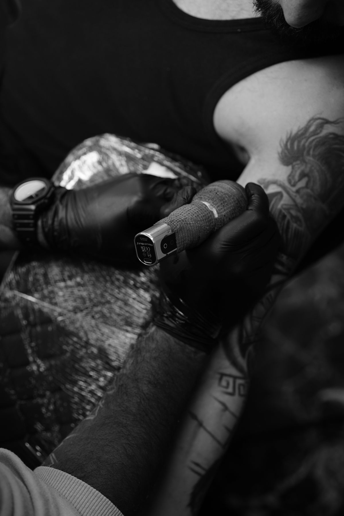 Tatuador trabajando en una pieza oscura en blanco y negro